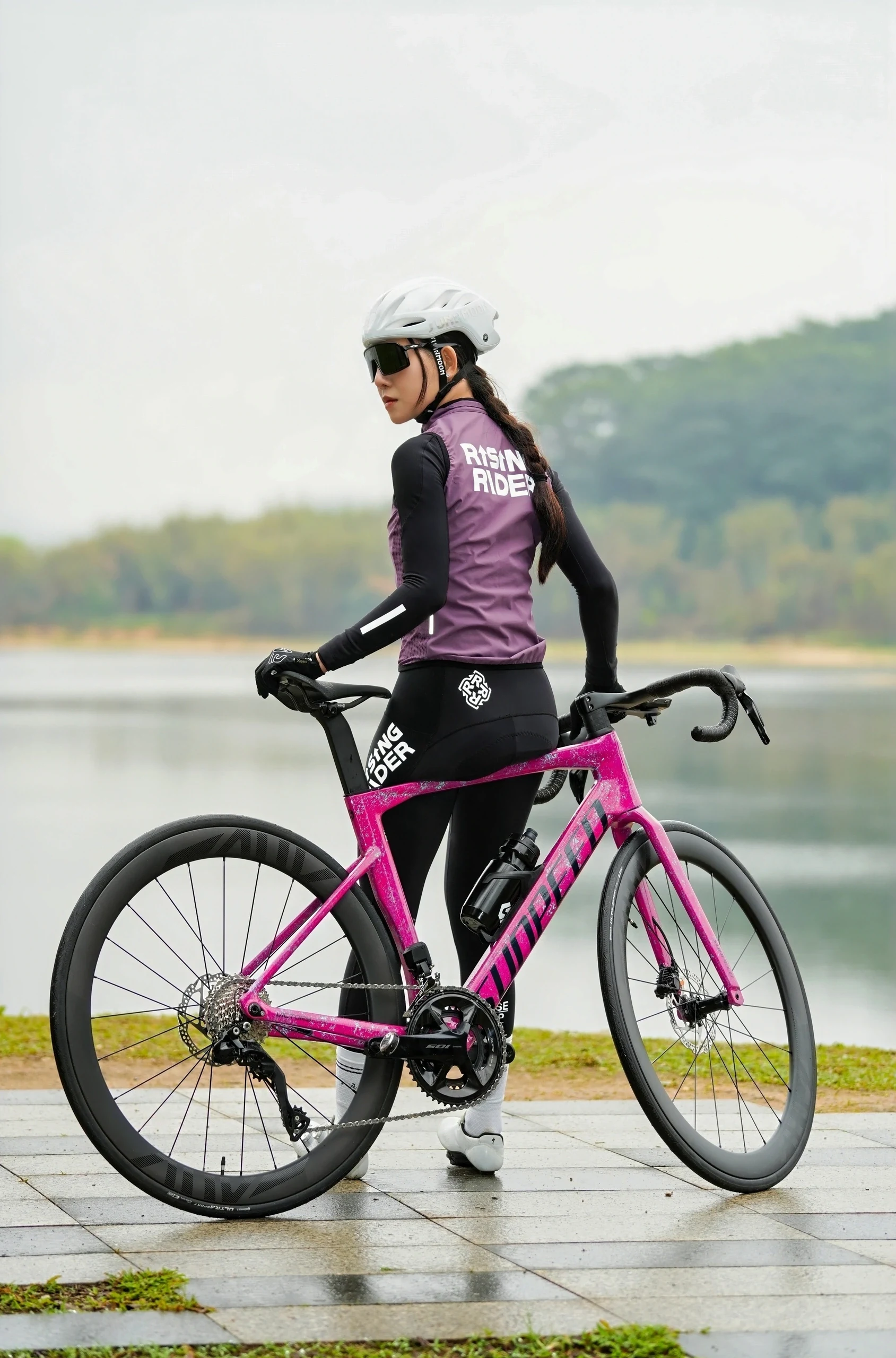 湖畔与粉色公路自行车同框的女性骑行者